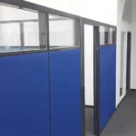 מחיצות אקוסטיות למשרד עם חיפוי בד כחול וחלון זכוכית עליון ליצירת מחיצות הפרדה למשרד